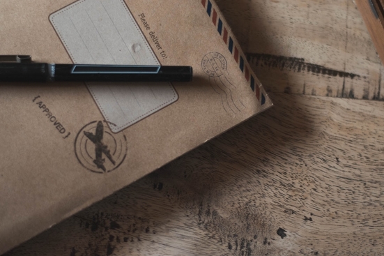 A pen on top of a brown envelope on a wooden surface