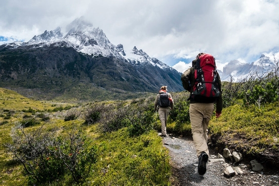 Two people photographed from behind hiking towards a mountain