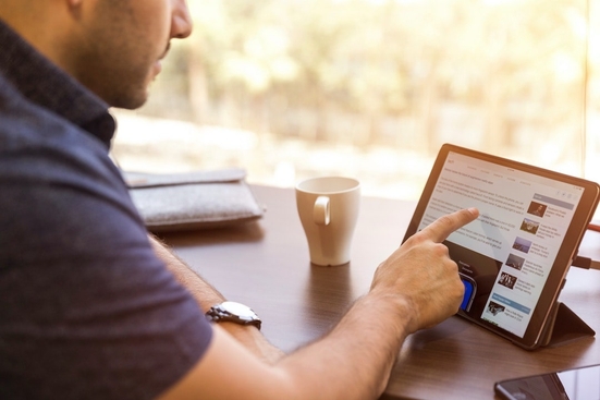 A man pointing at a tablet open to LinkedIn