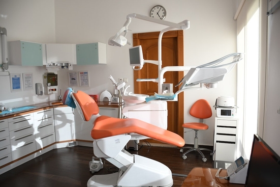 An sunny dentist's office featuring a bright orange patient chair